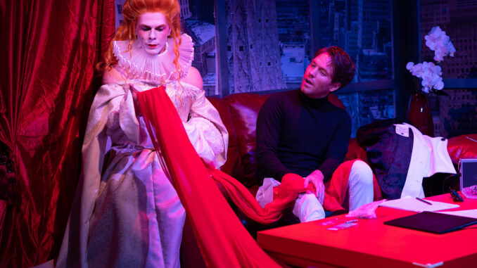 Queen for a Day 1. Photo by Rick Aguilar Studios Queen Elizabeth sits on a couch with Halston and admires a piece of red fabric